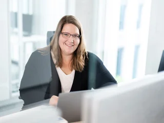 Arbeiten am Computer bei Tageslicht Eine Person mit langen Haaren sitzt an einem Schreibtisch und arbeitet an einem Computer.