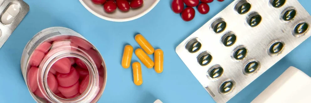 Hausapotheke zwischen Natur und Medizin Verschiedene Medikamente, Kräuter und medizinische Utensilien flach auf hellblauem Hintergrund arrangiert.