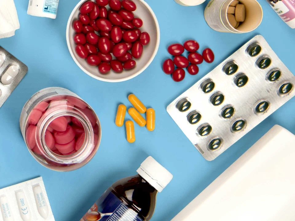 Hausapotheke zwischen Natur und Medizin Verschiedene Medikamente, Kräuter und medizinische Utensilien flach auf hellblauem Hintergrund arrangiert.